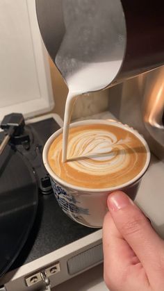 someone is pouring milk into a cup of coffee on the stove with an oven in the background