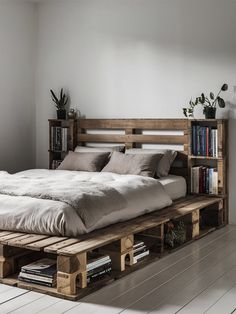 a bed made out of wooden pallets with bookshelves on each side and plants in the middle