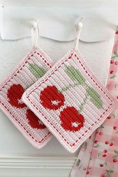 two crocheted red cherries hanging from hooks