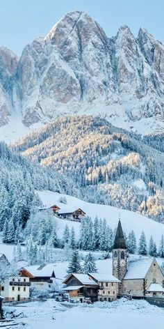 the mountains are covered in snow and there is a church on the hill next to it