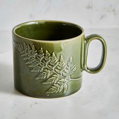 a green ceramic mug with leaves on it