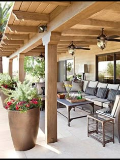 an outdoor living area with couches, tables and potted plants on the patio