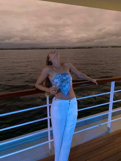 a woman standing on the deck of a boat with her arms outstretched and eyes closed