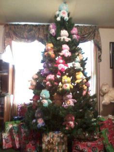 a christmas tree with stuffed animals on it in front of a window filled with presents