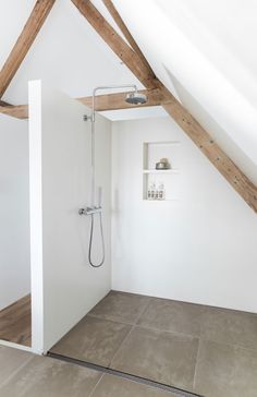 an attic bathroom with exposed wood beams and tile flooring, along with a shower