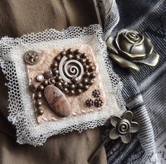 a close up of a decorative object on a cloth with beads and other items around it