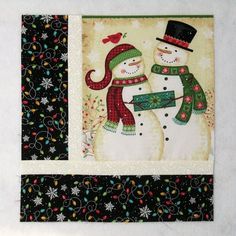 two snowmen are standing next to each other on a black and white wall hanging