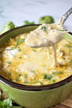 broccoli and cheese dip being scooped from a green casserole dish