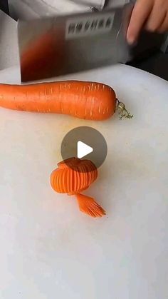 a person is cutting carrots with a knife on a white counter top, while another person holds a sharp knife in the background