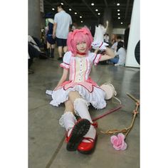 a woman dressed in pink and white sitting on the ground with her legs crossed, wearing red shoes