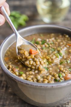 a spoon full of lentula soup with carrots and parsley on the side