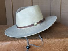 This 100% wool felt fedora is classically styled. Ready for your outdoor adventure! Perfect styling for a man or a woman. Simple leather hatband that is finished with a replicated Buffalo Nickel Concho. It has a stampede string to keep your hat on your head when the wind kicks up. Water resistant and crushable. The brim is 3.5" and the crown is 4.5" This hat ships within 2 - 3 days. Introduced in 1913, the Buffalo Nickel was an early hit with collectors and a major circulation workhorse through Western Felt Hat With Adjustable Fit And Short Brim, Western Style Adjustable Fit Felt Hat With Short Brim, Adjustable Fedora Felt Hat For Country Events, Western Style Felt Hat With Adjustable Short Brim, Adjustable Felt Hat With Flat Crown For Outdoor, Adjustable Fur Felt Fedora For Outdoor, Adjustable Outdoor Fedora In Fur Felt, Adjustable Outdoor Fur Felt Fedora, Adjustable Western Felt Hat For Outdoor