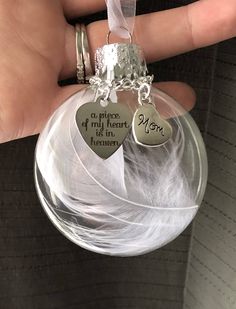 a person holding a glass ornament with two heart charms on it's side