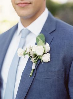 a man in a suit and tie with flowers on his lapel