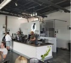 people sitting at tables in a restaurant with food on the counter and an open kitchen area