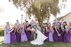 a bride and groom posing with their bridal party in front of a large tree