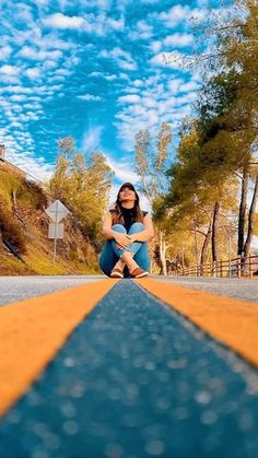 a woman sitting on the side of an empty road