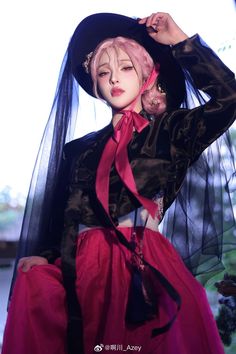 a woman with pink hair wearing a black and red dress, hat and veil over her head