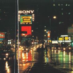 a city street at night with lots of lights and signs on the side of it