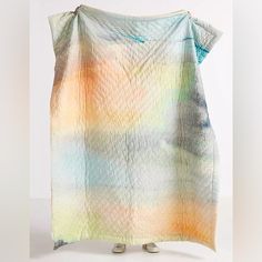 a colorful blanket is draped in front of a white background with an orange, blue and yellow pattern