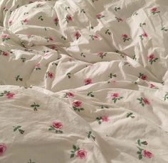 an unmade bed with pink roses on it