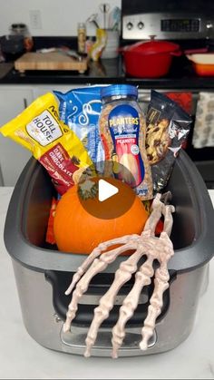 a plastic container filled with halloween treats and skeleton hands on top of the trash can