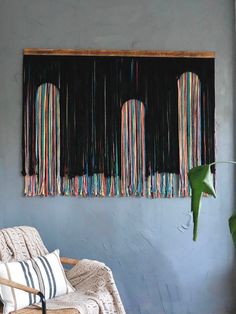 a room with a chair, rug and wall hanging on the wall next to a potted plant