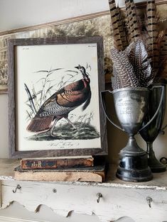 a bird sitting on top of a mantle next to a trophy and some feathers in a vase