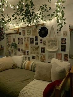 a living room filled with lots of pillows and plants hanging from the ceiling above it