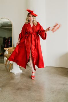 byVINNIK designer SUZANNE VINNIK wearing red sparkling Parisian Coat paired with red Fluevog Dee Munsters and a handmade red feather fascinator holding a rose Papagena feather clutch taking a step away from mirror Jacquard Coat, French Couture, Downtown Los Angeles