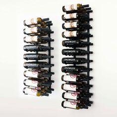 two rows of wine bottles sitting next to each other on a white wall with red and black lettering