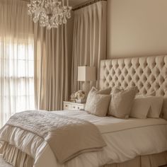 a bedroom with a bed, chandelier and curtains