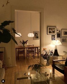 a living room filled with furniture next to a dining room table and lamp on top of a hard wood floor