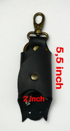 a black leather keychain with brass hardware on the front and back ends, attached to a metal hook