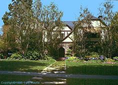 a house with trees and bushes in front of it on a clear blue sky day