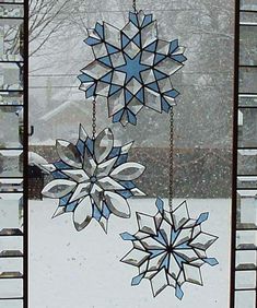 three snowflakes hanging from a window in the snow