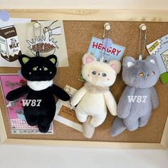 three stuffed animals are hanging on a cork board