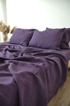 a bed covered in purple sheets and pillows