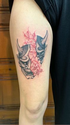 a woman's thigh with a tattoo on it that has two skulls and flowers