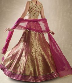 This exquisite Purple Pink Embroidered Banarasi Lehenga Set is crafted from luxurious Banarasi fabric, featuring rich kalidar purple pink lehenga adorned with a striking mirror-embellished belt and border that add a glimmer of sophistication to its traditional weave. Teamed with a classic mirror work blouse, intricately embellished with dori, mirrors, beads, and sequins, exuding an opulent charm. A lightweight tulle dupatta completes the look, delicately sprinkled with mirror buttis and finished Elegant Pink Chanderi Choli, Transitional Pink Tissue Silk Lehenga, Bollywood Brocade Salwar Kameez For Reception, Purple Brocade Bollywood Sets, Transitional Pink Raw Silk Choli, Purple Bollywood Brocade Sets, Gold Banarasi Silk Choli With Intricate Embroidery, Pink Brocade Saree For Reception, Bollywood Brocade Anarkali Set For Reception