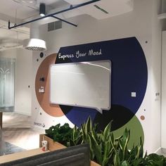 an office with plants in the foreground and a sign on the wall that says express your mood