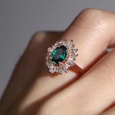 a woman's hand with an emerald and diamond ring