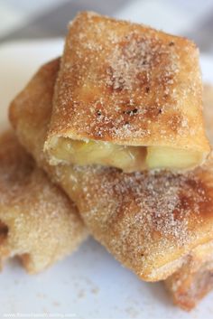 three pieces of food sitting on top of a white plate covered in powdered sugar