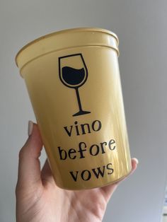 a person holding up a cup that says vino before vows on the side