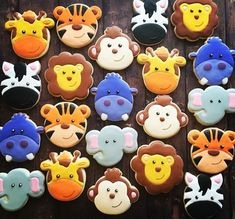 many decorated cookies are arranged on a table with different colors and shapes, including zebras, giraffes, monkeys, and other animals