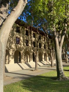 an old building with steps leading up to it and trees lining the sidewalk in front