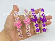 three pieces of pink and purple butterfly broochies in gold tone setting on hand