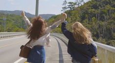 two women walking down the road with their arms in the air