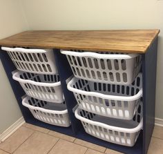 three white laundry baskets stacked on top of each other in front of a wooden counter