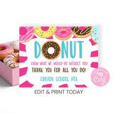 a pink box filled with donuts on top of a white table next to a card